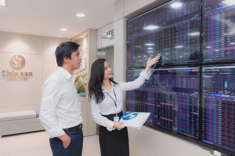 Nhà đầu tư theo dõi bảng điện chứng khoán tại công ty môi giới
