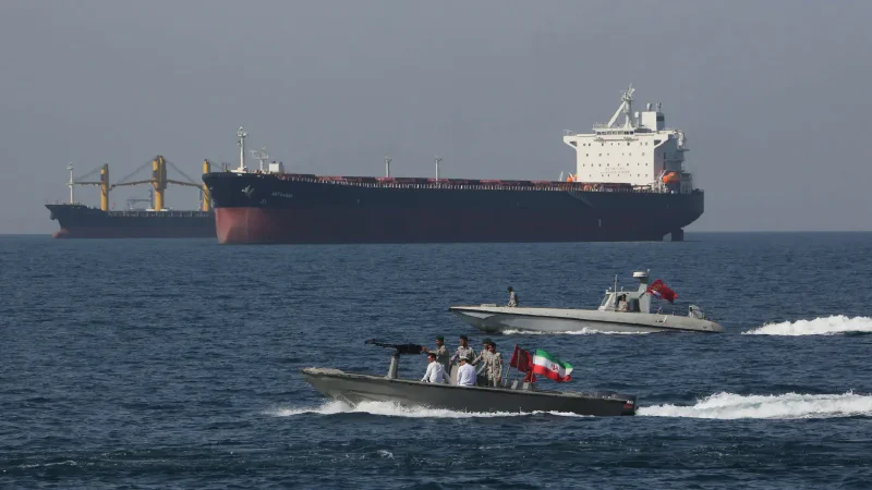 Oil tanker passing through the Strait of Hormuz with military patrol